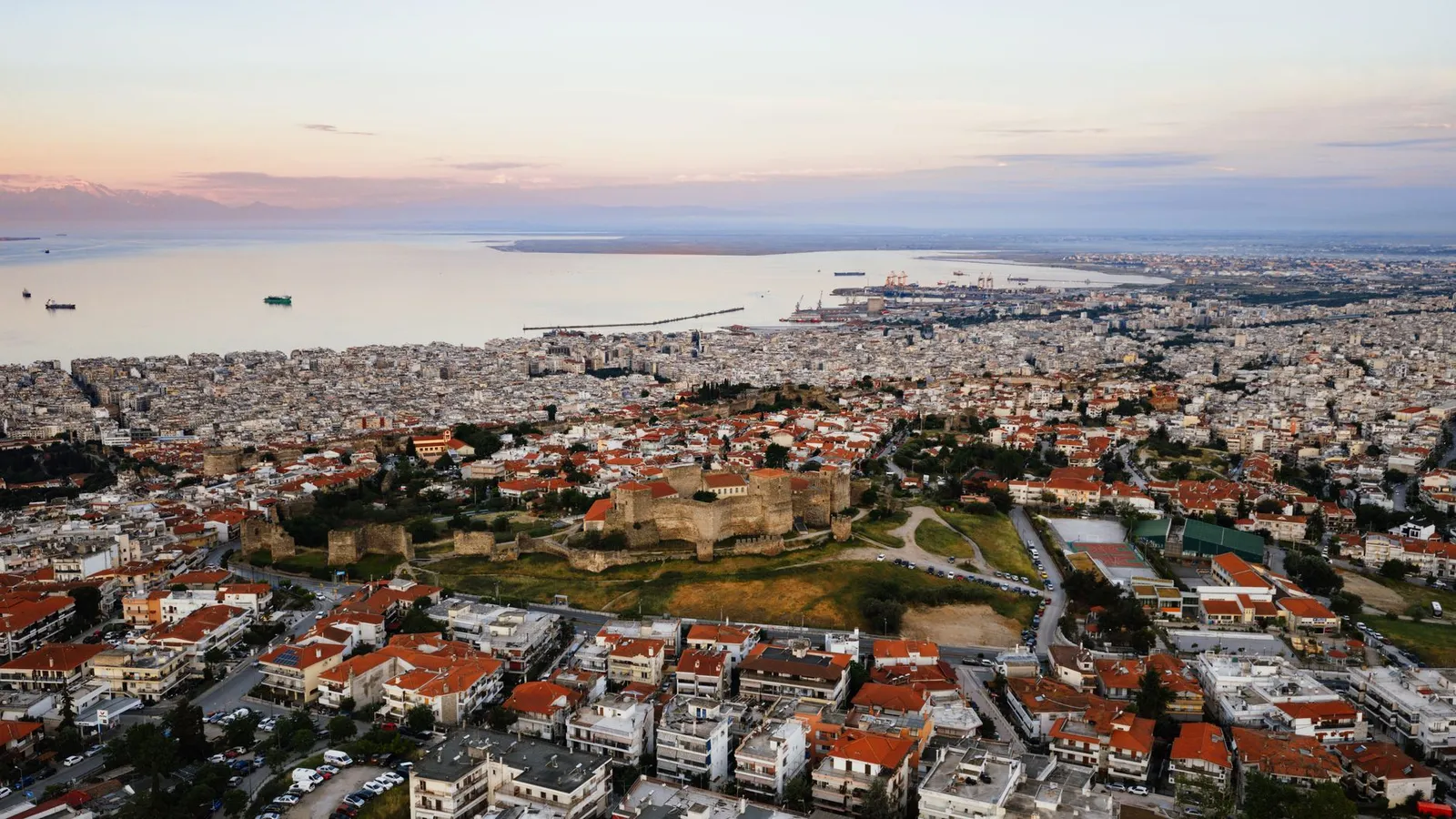 Aerial view of the historic city of Thessaloniki, Greece at sunset showing the cityscape and coast.