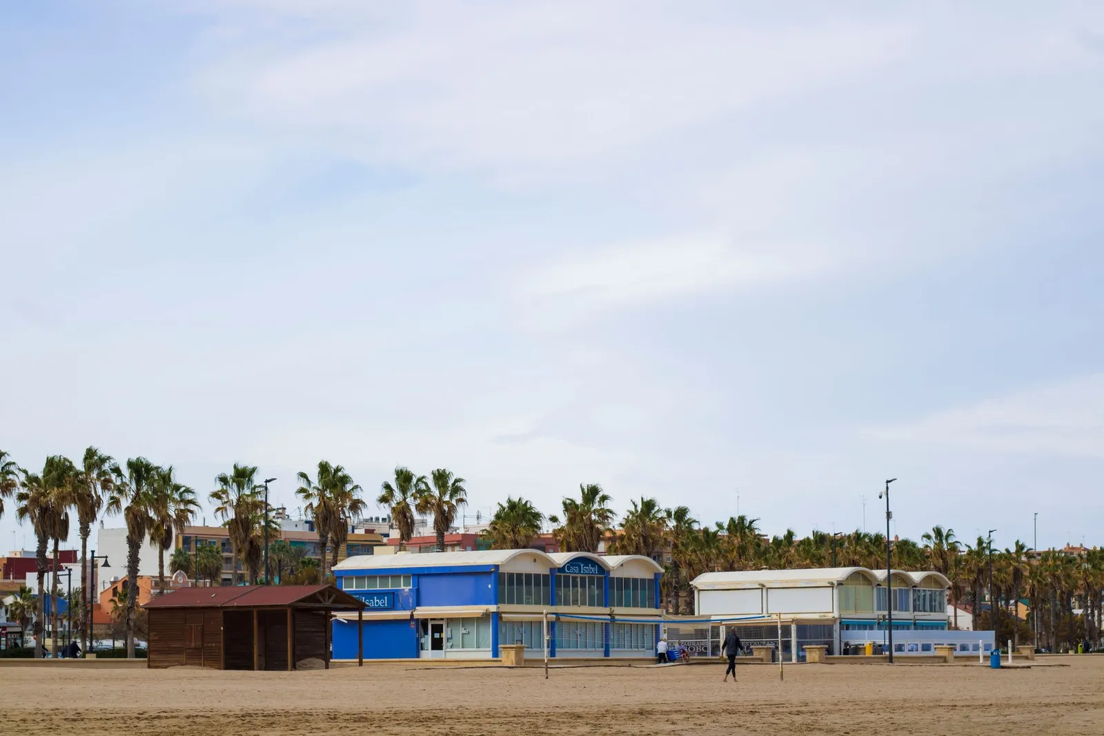 Tranquil beachfront scene in Valencia, Spain, featuring palm trees and dining establishments.