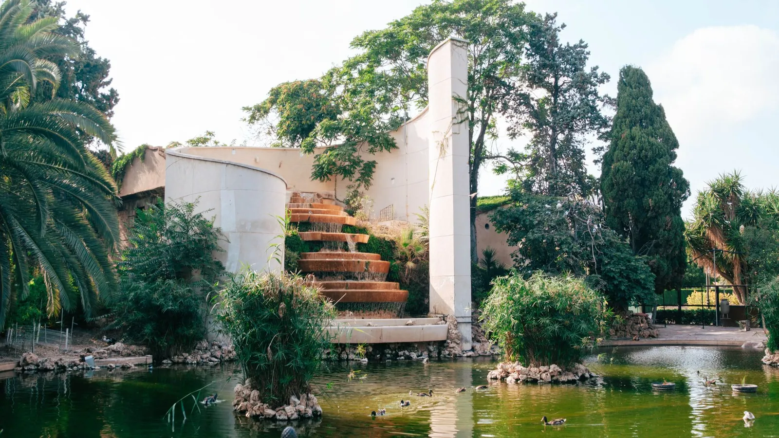 A beautiful waterfall surrounded by lush greenery in València's Jardín del Turia park.