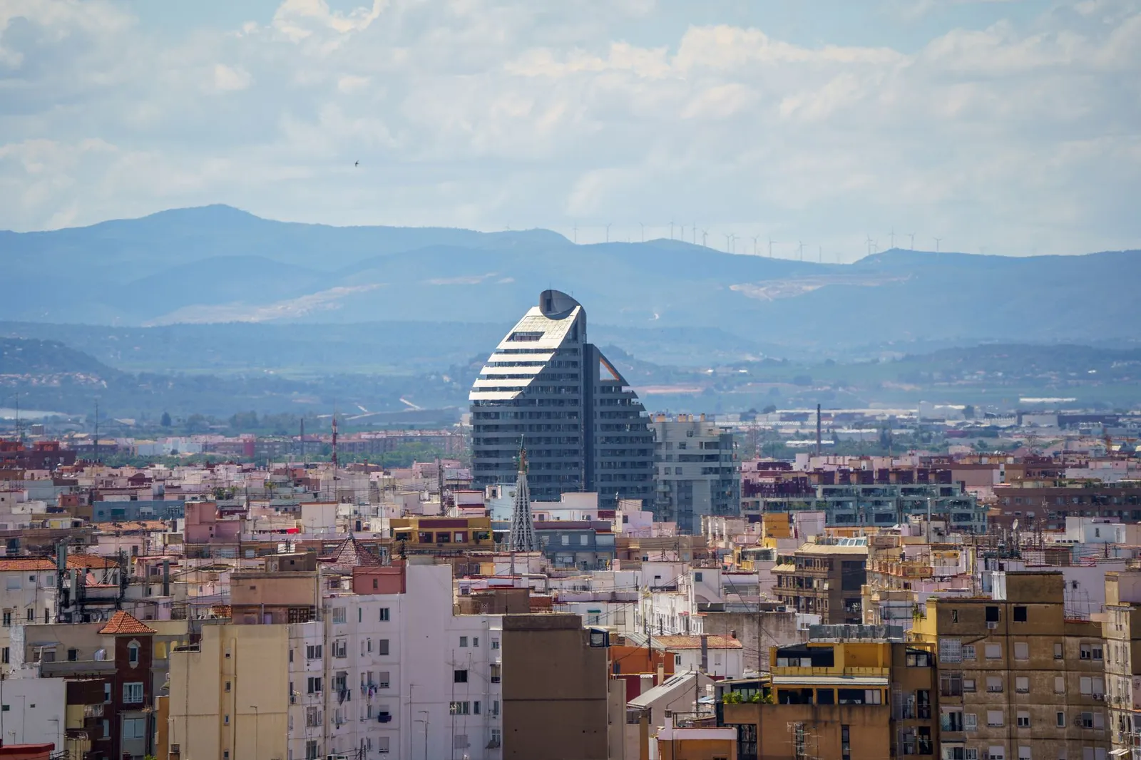 A stunning aerial view of Valencia, Spain featuring the prominent Navis Building against a mountainous backdrop.