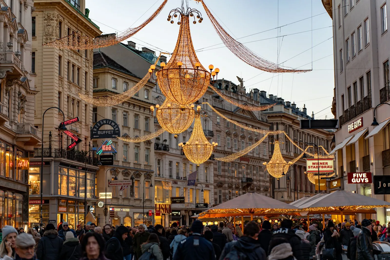Twinkling chandeliers and bustling crowds create a festive vibe on Graben Street, Vienna during winter.
