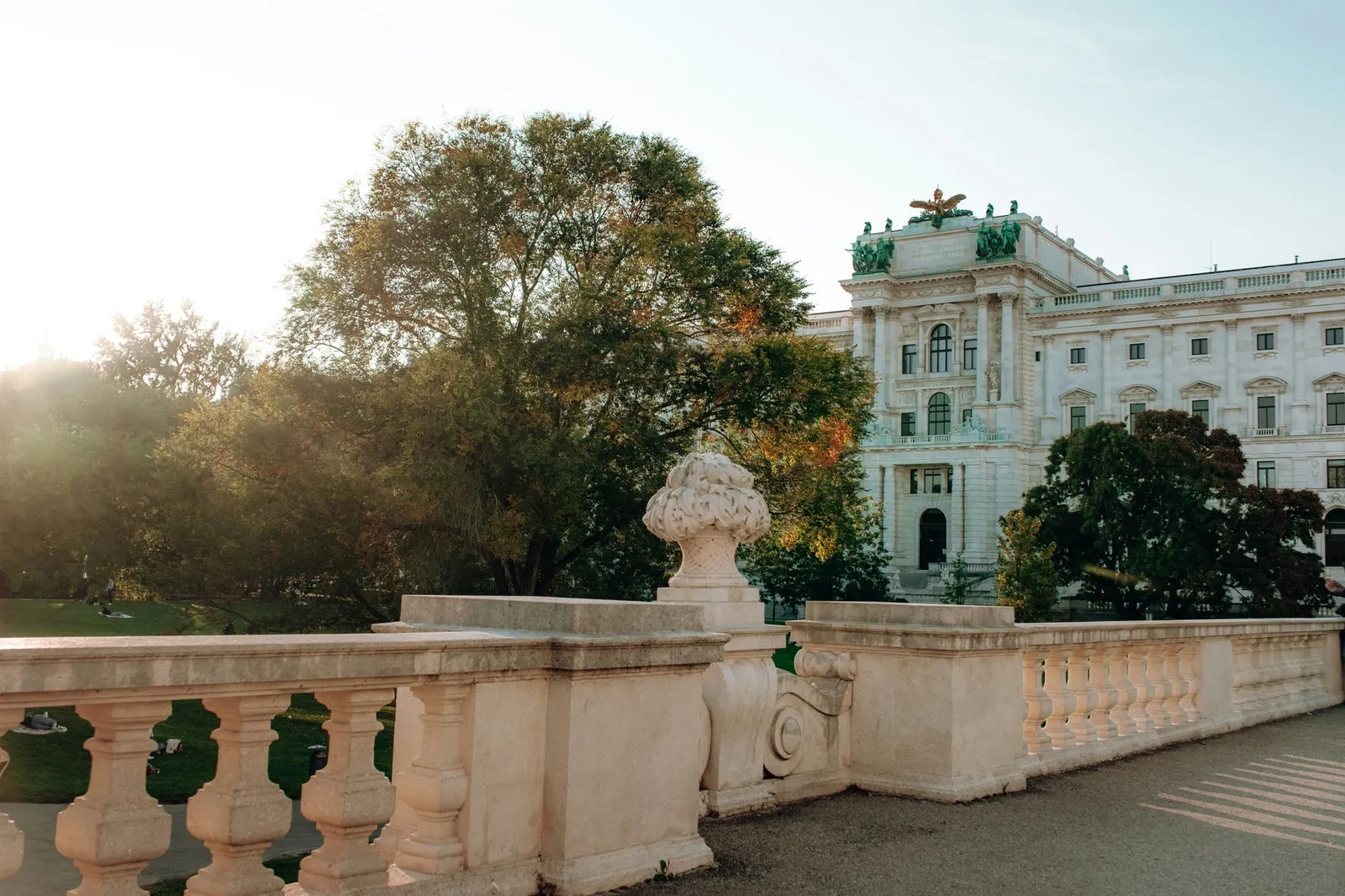 Sunlit view of Hofburg Palace in Vienna with lush greenery and classic architecture.