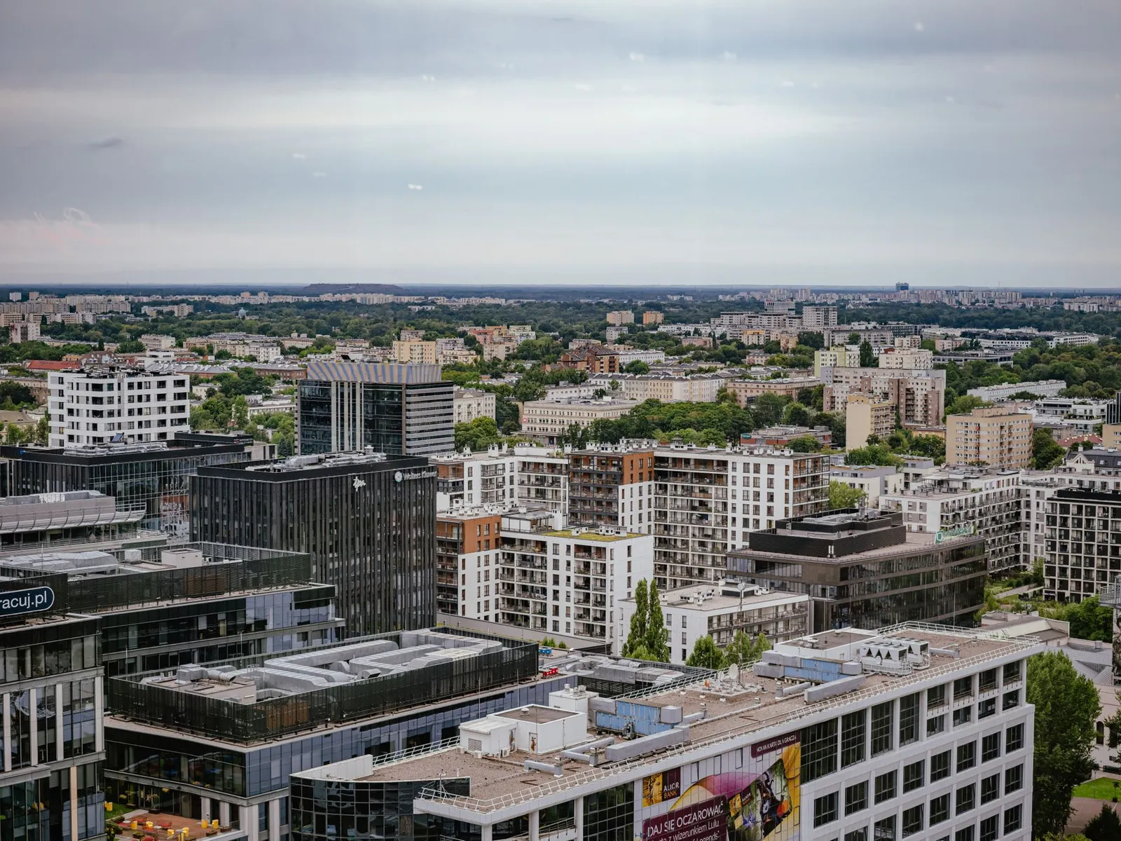 Aerial view of Warsaw showcasing modern and residential architecture against a lush backdrop.