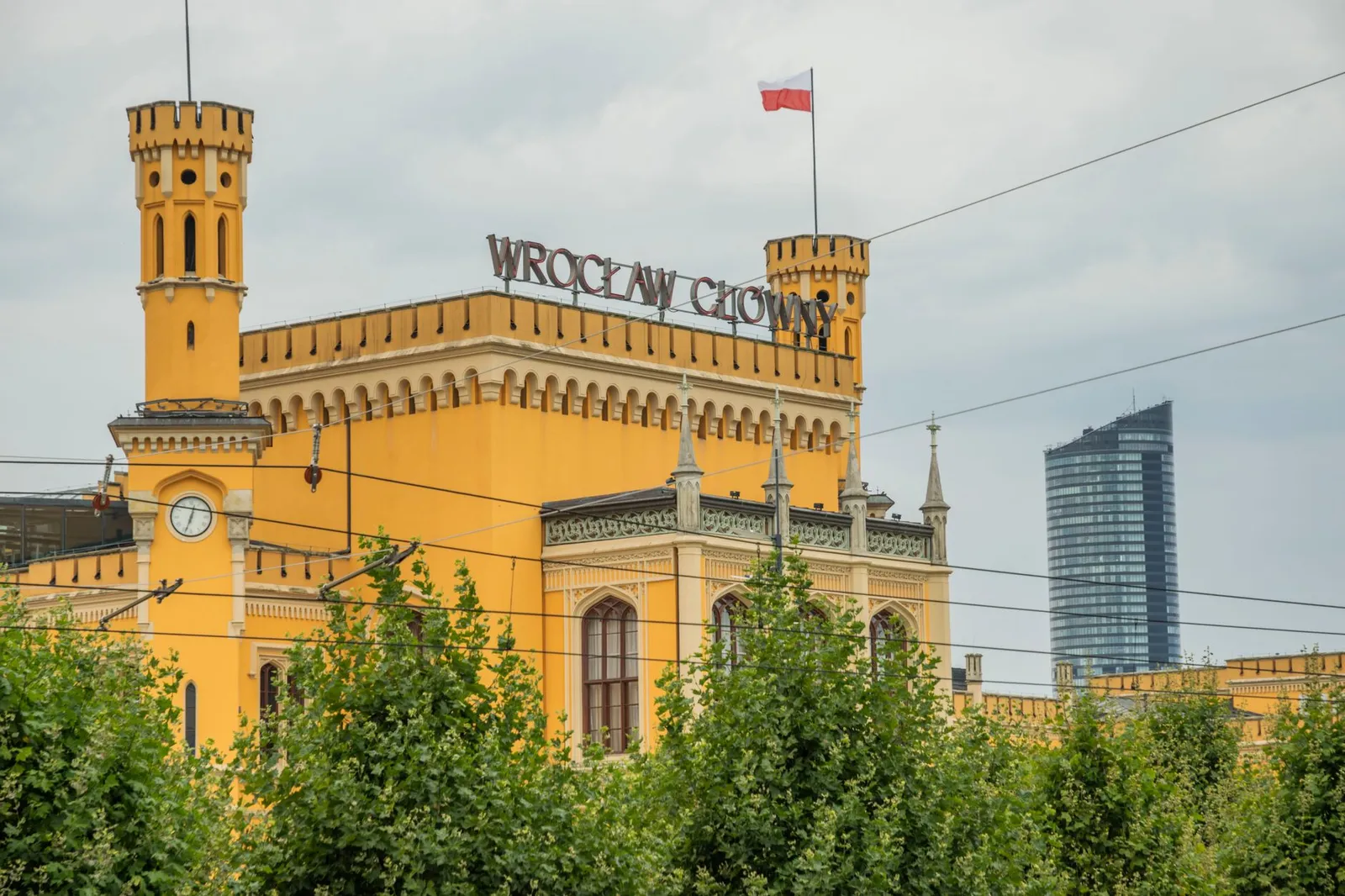 Wrocław Główny train station captured with its distinct architecture alongside a modern skyscraper.
