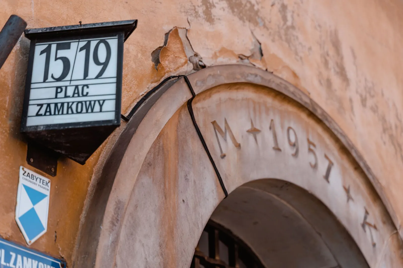 Close-up of a historic archway at Plac Zamkowy, displaying architectural details and signage.