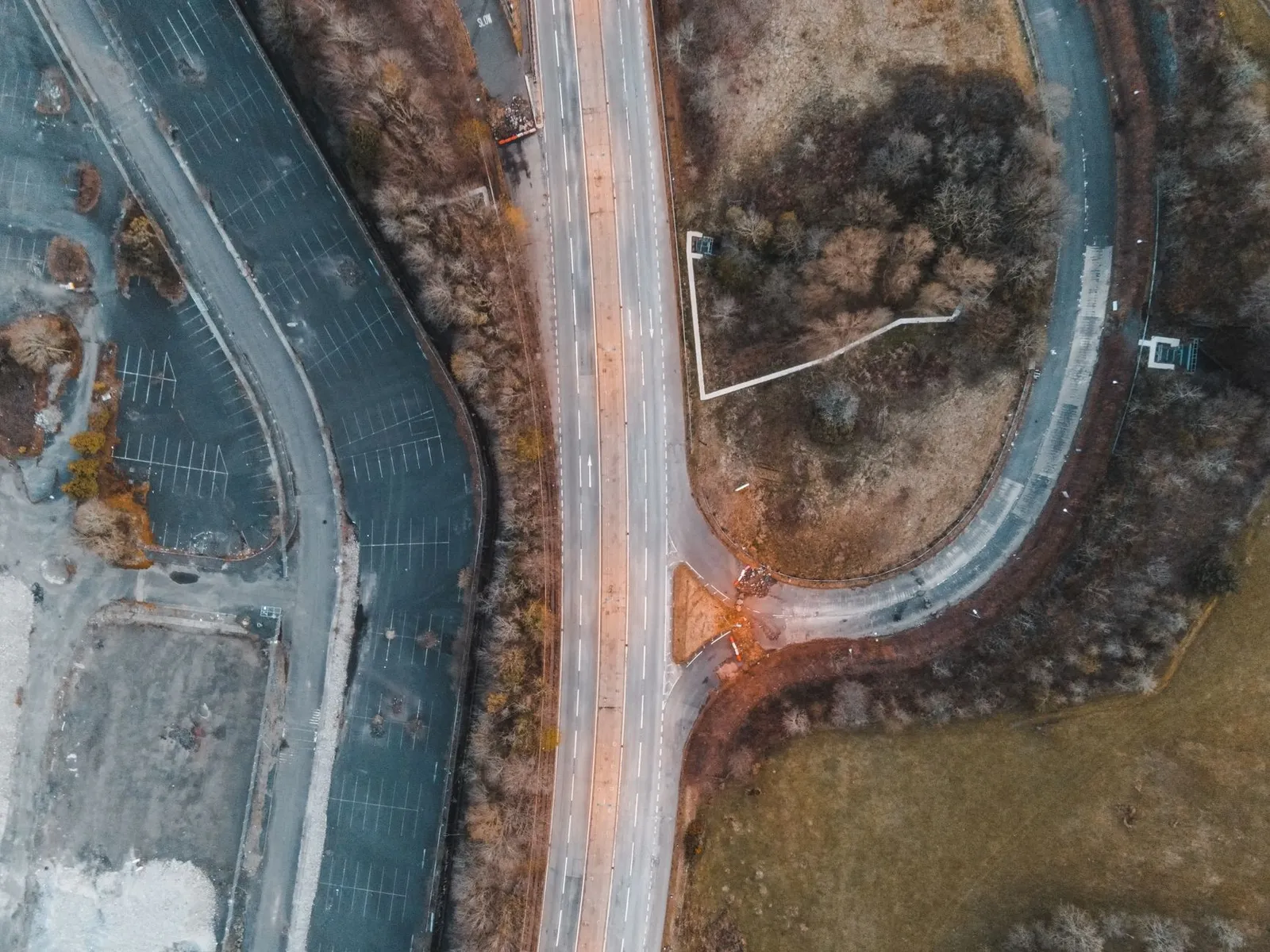 Drone shot of a road intersection surrounded by nature and parking areas in Scotland.